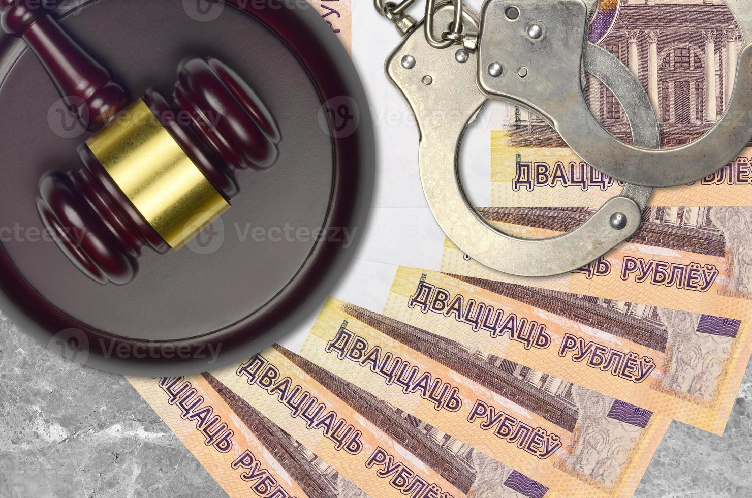 20 Belorussian rubles bills and judge hammer with police handcuffs on court desk. Concept of judicial trial or bribery. Tax avoidance photo