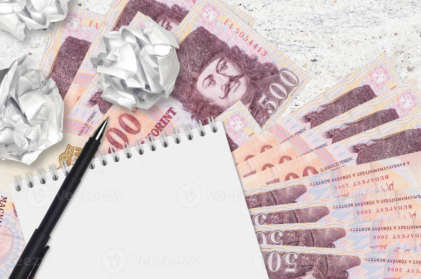 500 Hungarian forint bills and balls of crumpled paper with blank notepad. Bad ideas or less of inspiration concept. Searching ideas for investment photo