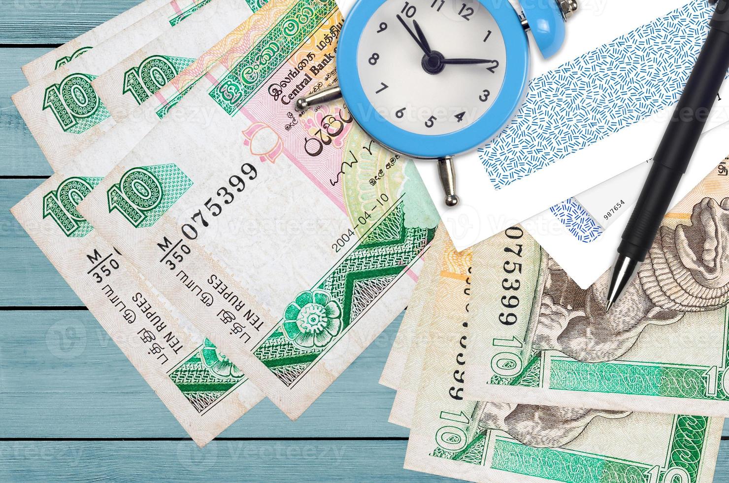 10 Sri Lankan rupees bills and alarm clock with pen and envelopes. Tax