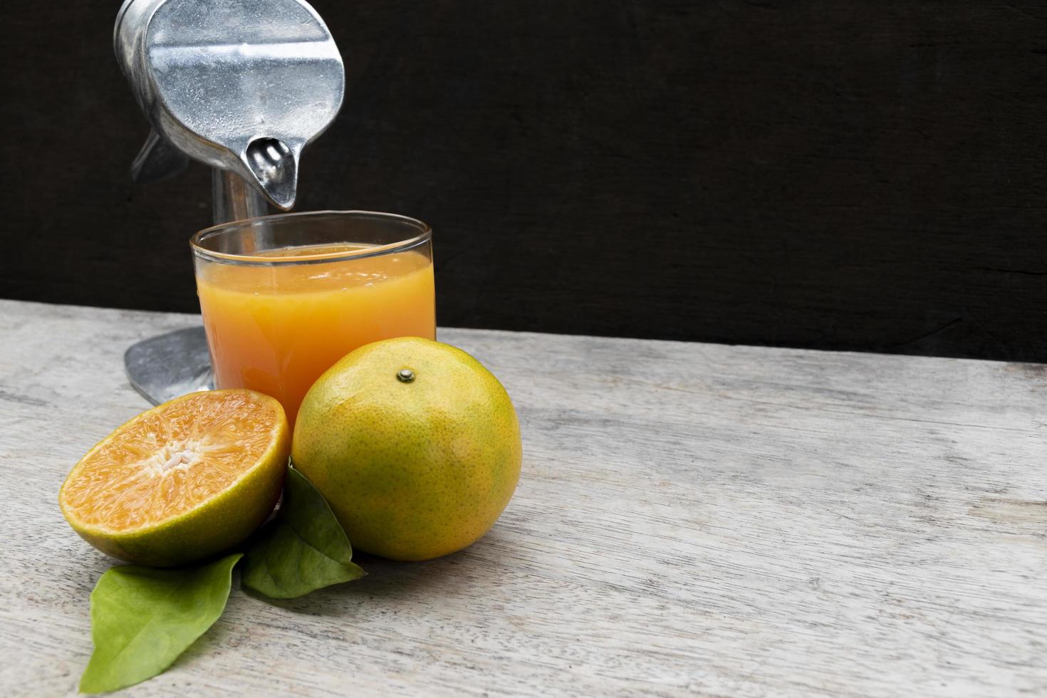 Orange juice in glass and fresh citrus around with Juicer hand press squeezer fruit on wood table. Copy space photo