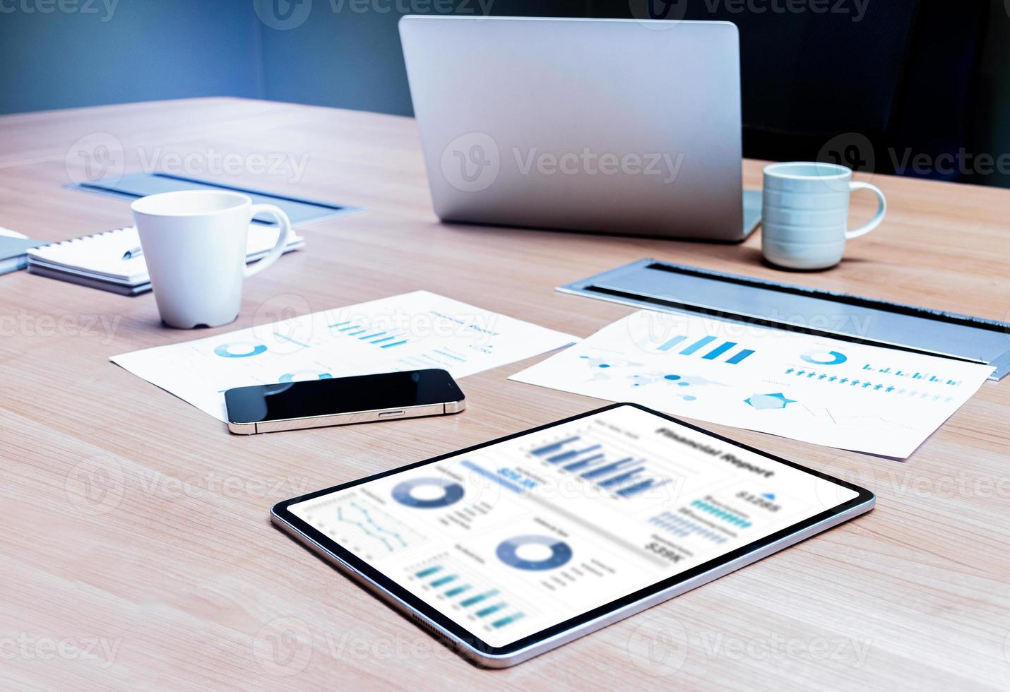 Mock up financial report slide show presentation on display tablet and paperwork ,smartphone ,coffee cup ,laptop on table in meeting photo