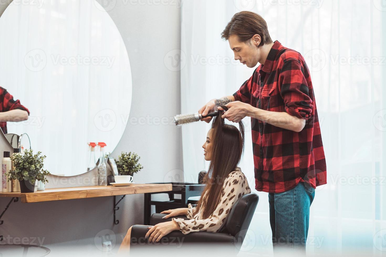 Hair stylist barber styling long hair with brush for beautiful asian young woman in beauty salon working moment photo