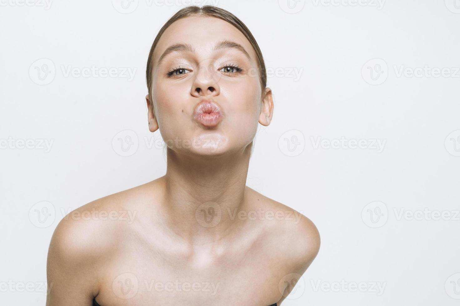 Beauty portrait of funny young girl with fresh skin tone showing kiss on white background isolated photo