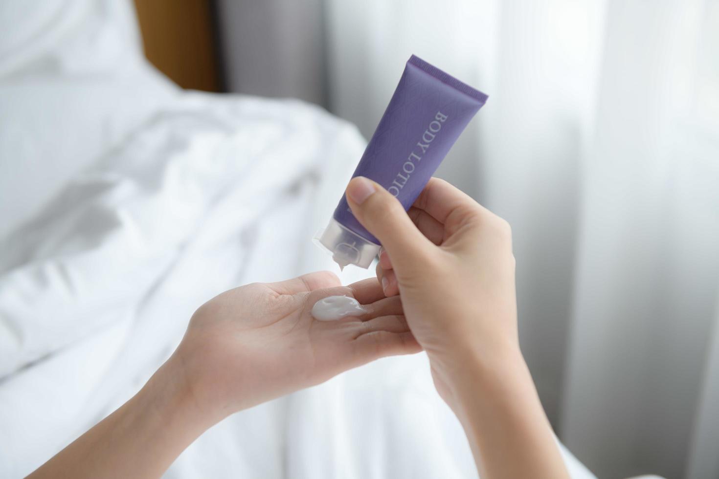 Close up of women applying body lotion cream on hand. photo