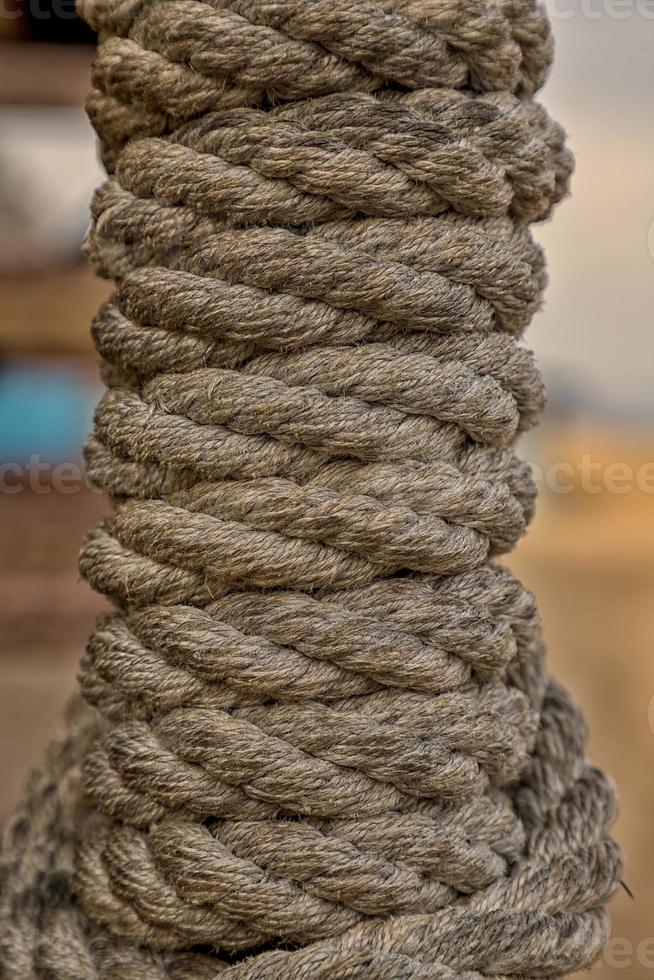 reeled rope on the coil. The texture of a rope. Thick brown rope rolled into a roll. Vertical layout. Background texture photo