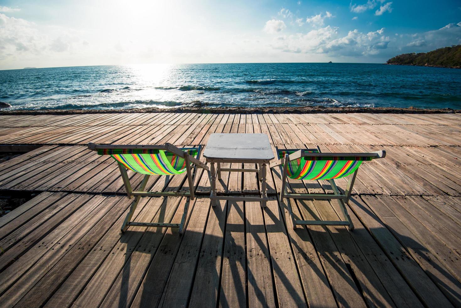 Terrace view of sea waves and coast landscape seascape with bench chair beach on wooden bridge balcony Tropical island with ocean blue sky background in Thailand summer beach vacation and table set - photo