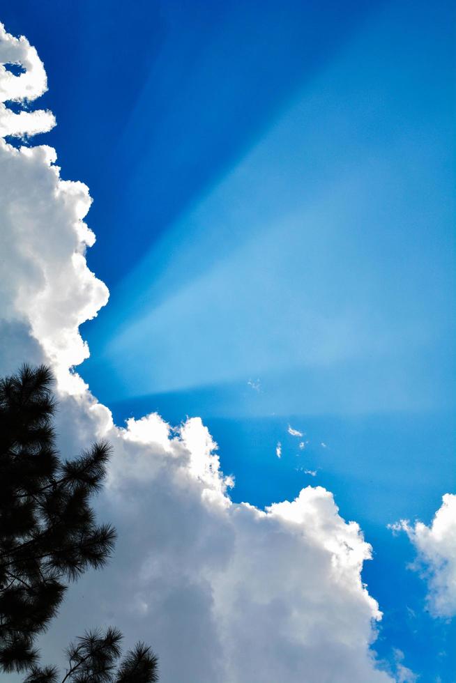 rayos de sol brillando con nubes y fondo de cielo azul foto