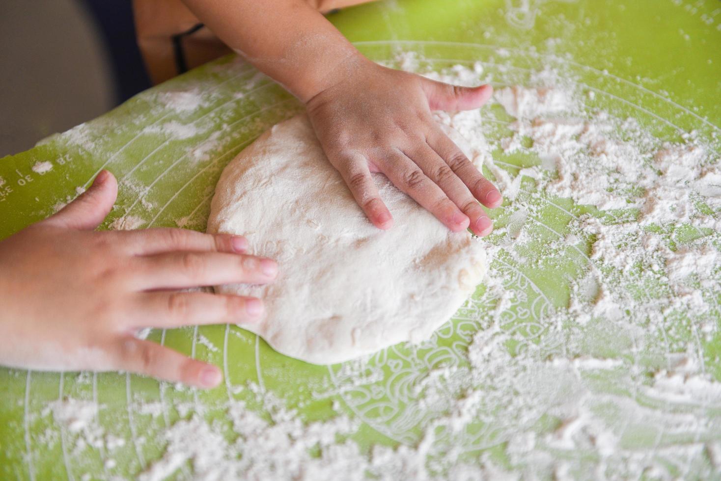 hands knead the dough homemade pastry for bread or pizza Bakery background - child hands prepares the dough with flour on board photo