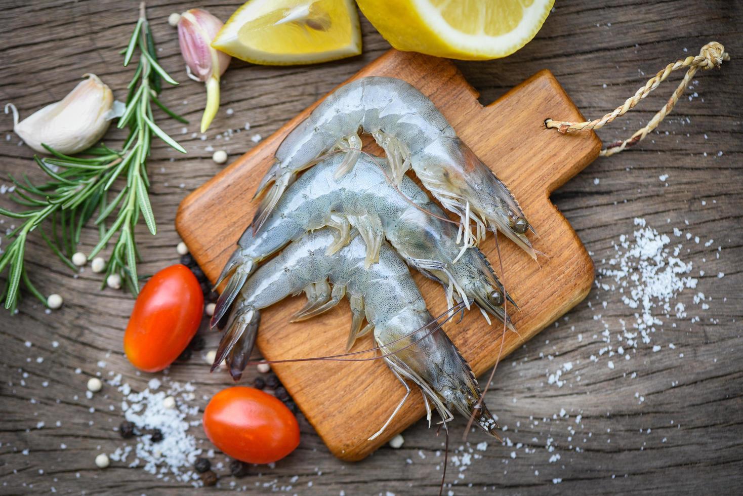 fresh shrimp on wooden cutting board with ingredients herb and spices for cooking seafood - raw shrimps prawns photo