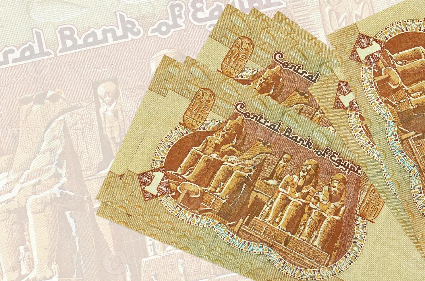 1 Egyptian pound bills lies in stack on background of big semi-transparent banknote. Abstract presentation of national currency photo