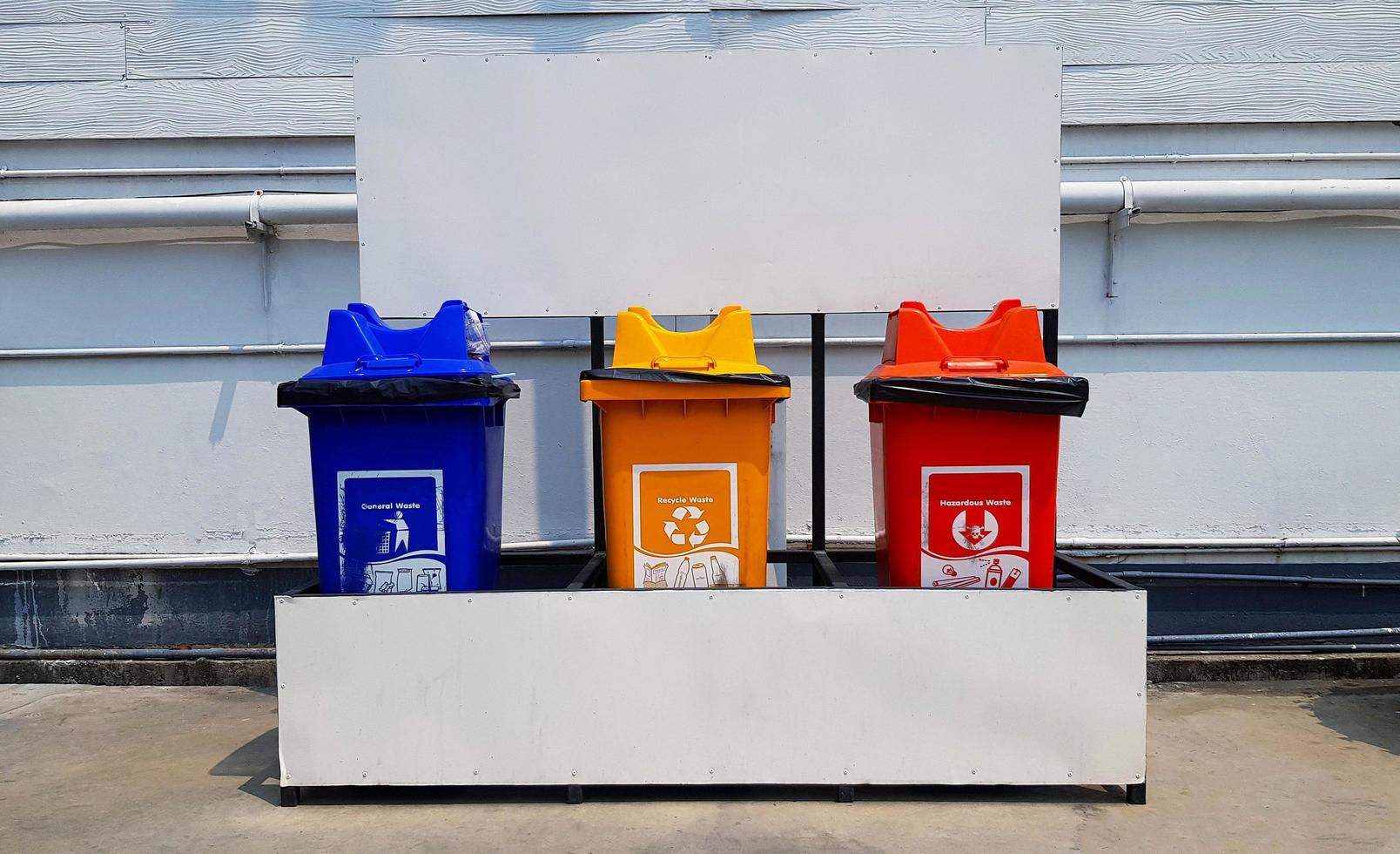 Colorful three bins for separate trash for reuse and disposal at park. Trashcan for dumping used stuff or material with white gas or oil pipeline background . photo