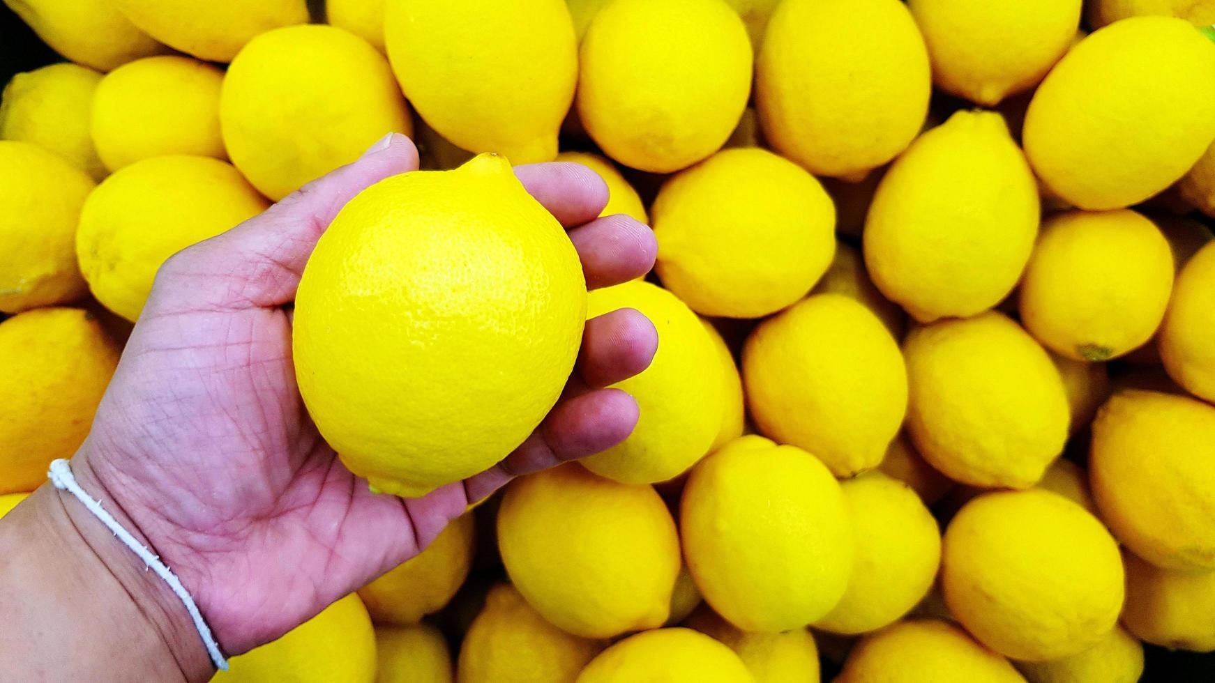 cerrar la mano de la persona que sostiene limón con espacio de copia. selección y elección para comprar la mejor comida, verdura o fruta en el mercado o supermercado. foto