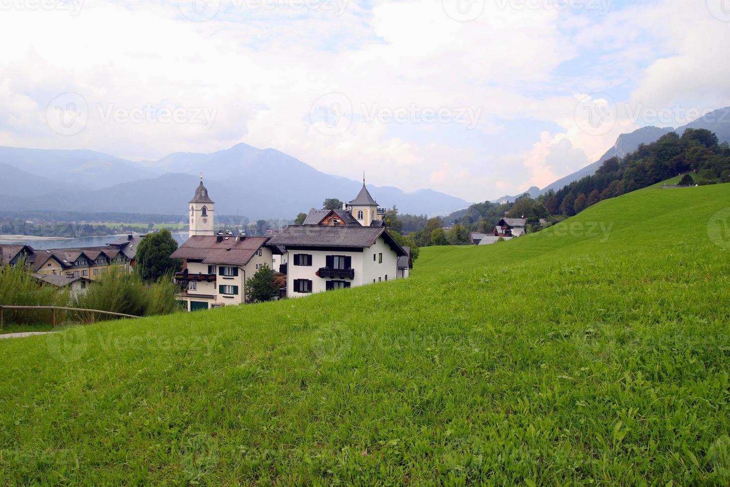 Travel to Sankt-Wolfgang, Austria. The green meadow with the houses in the mountains. photo