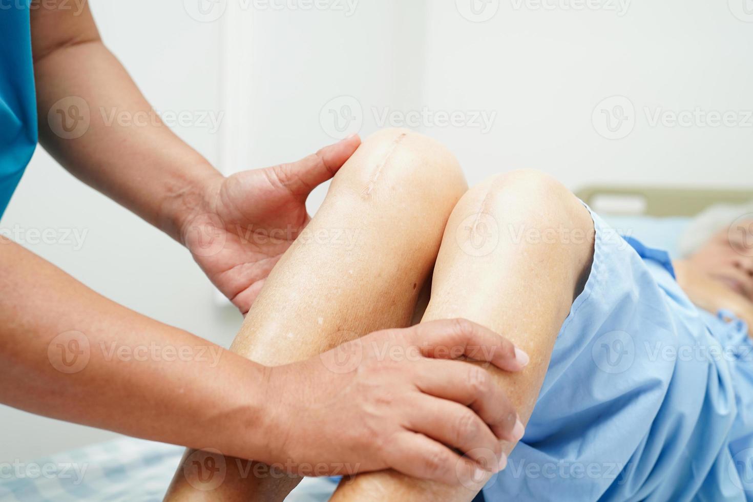 Doctor checking Asian elderly woman patient with scar knee replacement surgery in hospital. photo