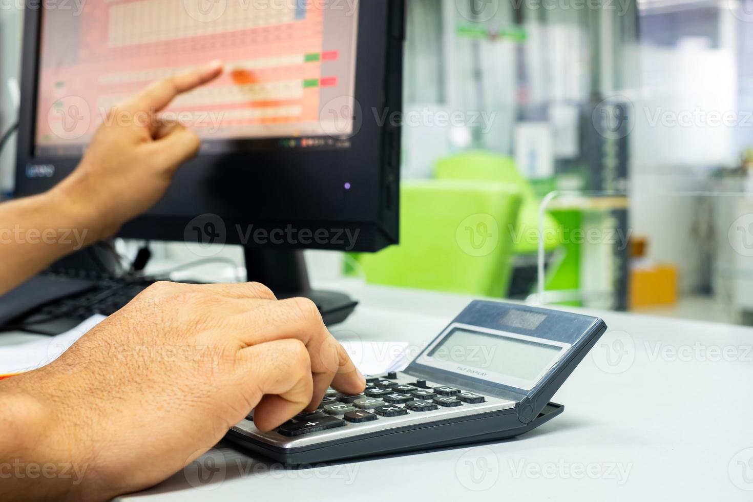 la mano del hombre está usando la calculadora para informar el trabajo en la computadora, para presentar el informe de ganancias comerciales, el concepto de negocios y finanzas. foto