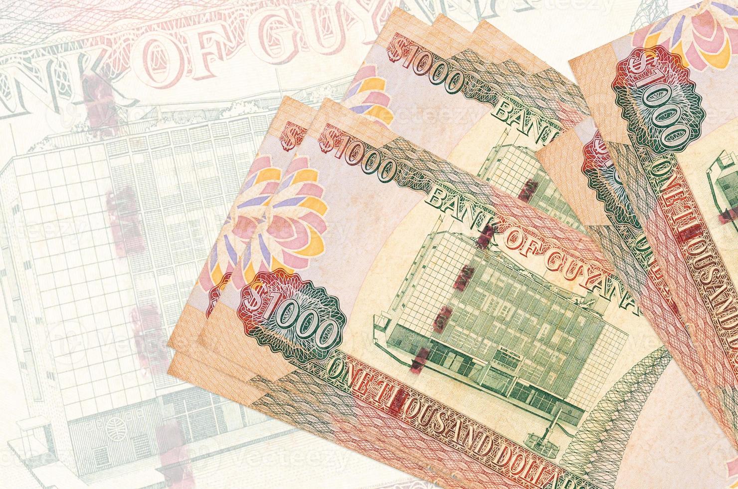 1000 Guyanese dollars bills lies in stack on background of big semi-transparent banknote. Abstract presentation of national currency photo
