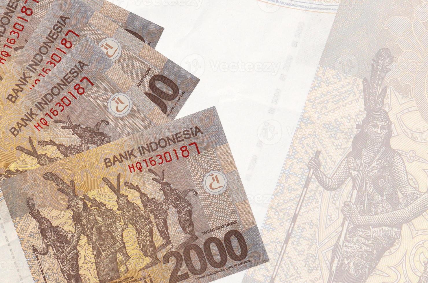 Los billetes de 2000 rupias indonesias se encuentran apilados sobre el fondo de un gran billete semitransparente. fondo de negocios abstracto foto