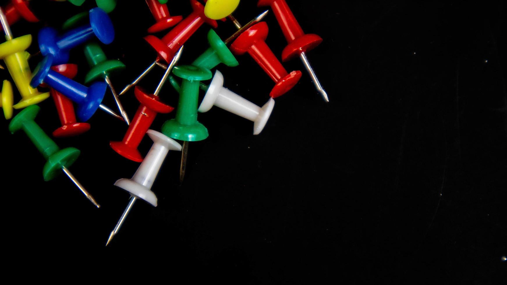 multicolored thumbtacks on a black background photo