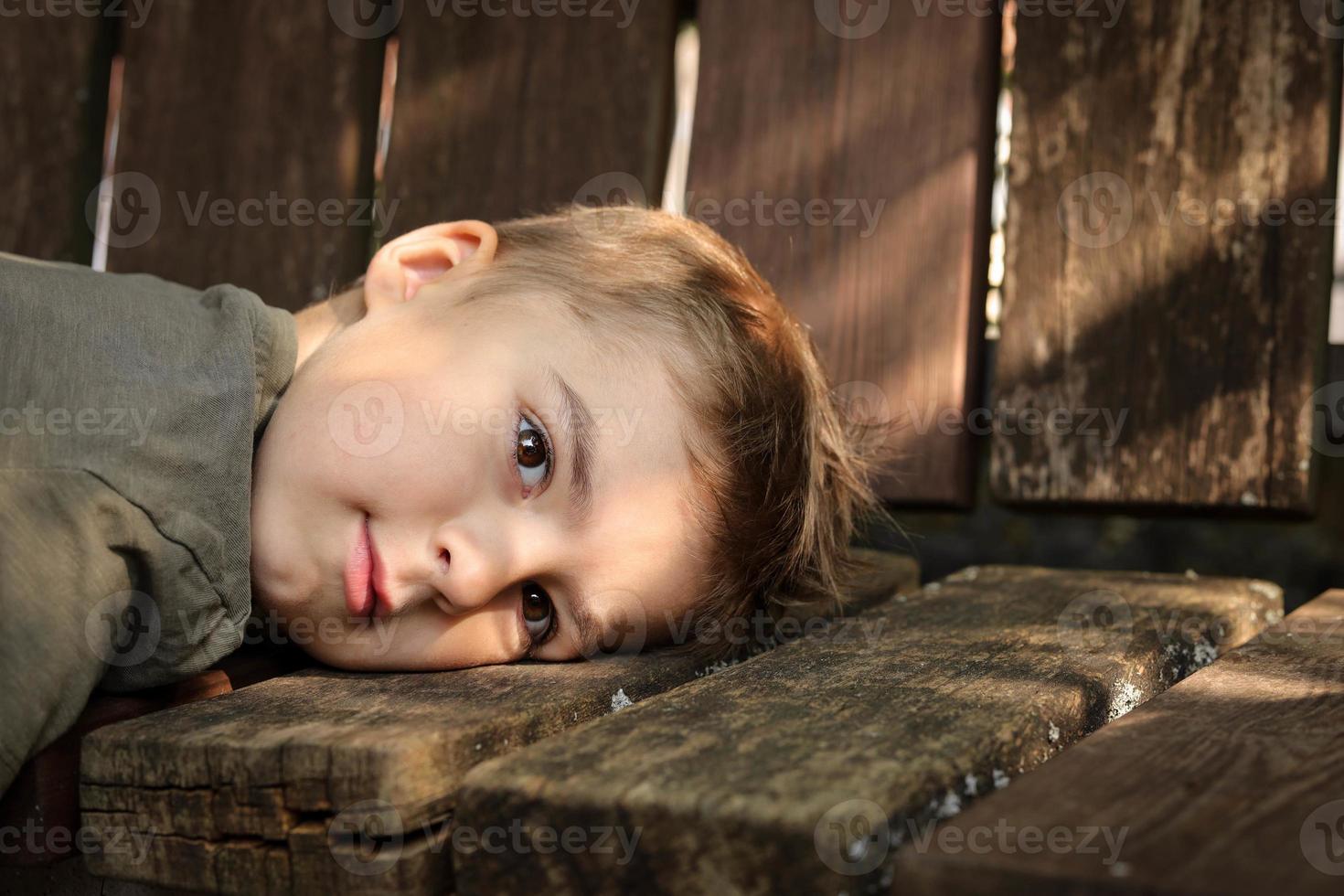 Portrait of little adorable boy. Cute child, dreaming, thinking about something. Beautiful brown eyes. Close up view. Children dreams and wishes. Mysterious light, outdoor portrait. Missing someone. photo