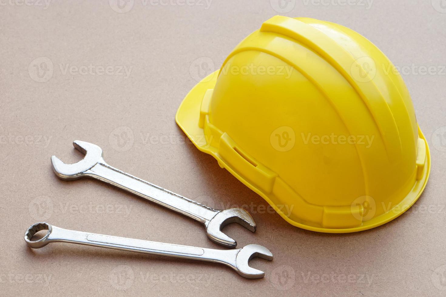 Yellow helmet and wrenches on brown background. Concept, handyman or mechanic tools. Equipment for fixing or repairing, renovation in daily life. photo