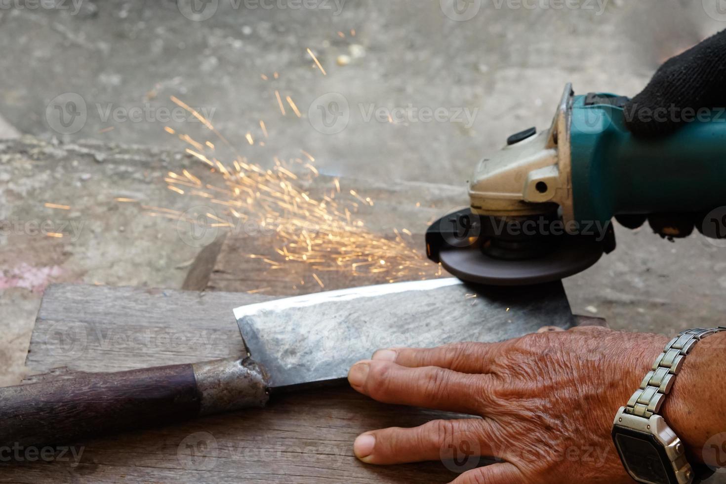 Closeup hands are sharpening a knife with electric sharpener grinder