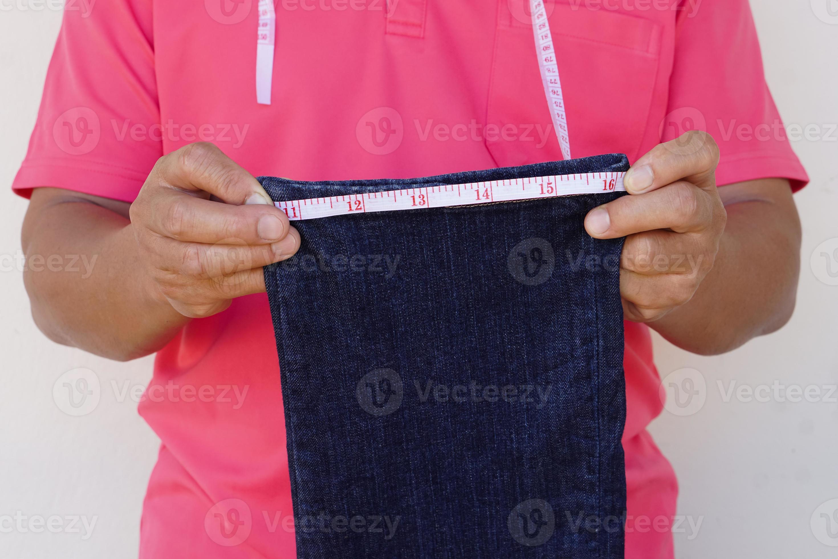 Closeup tailor hand use measuring tape to measure width of jeans