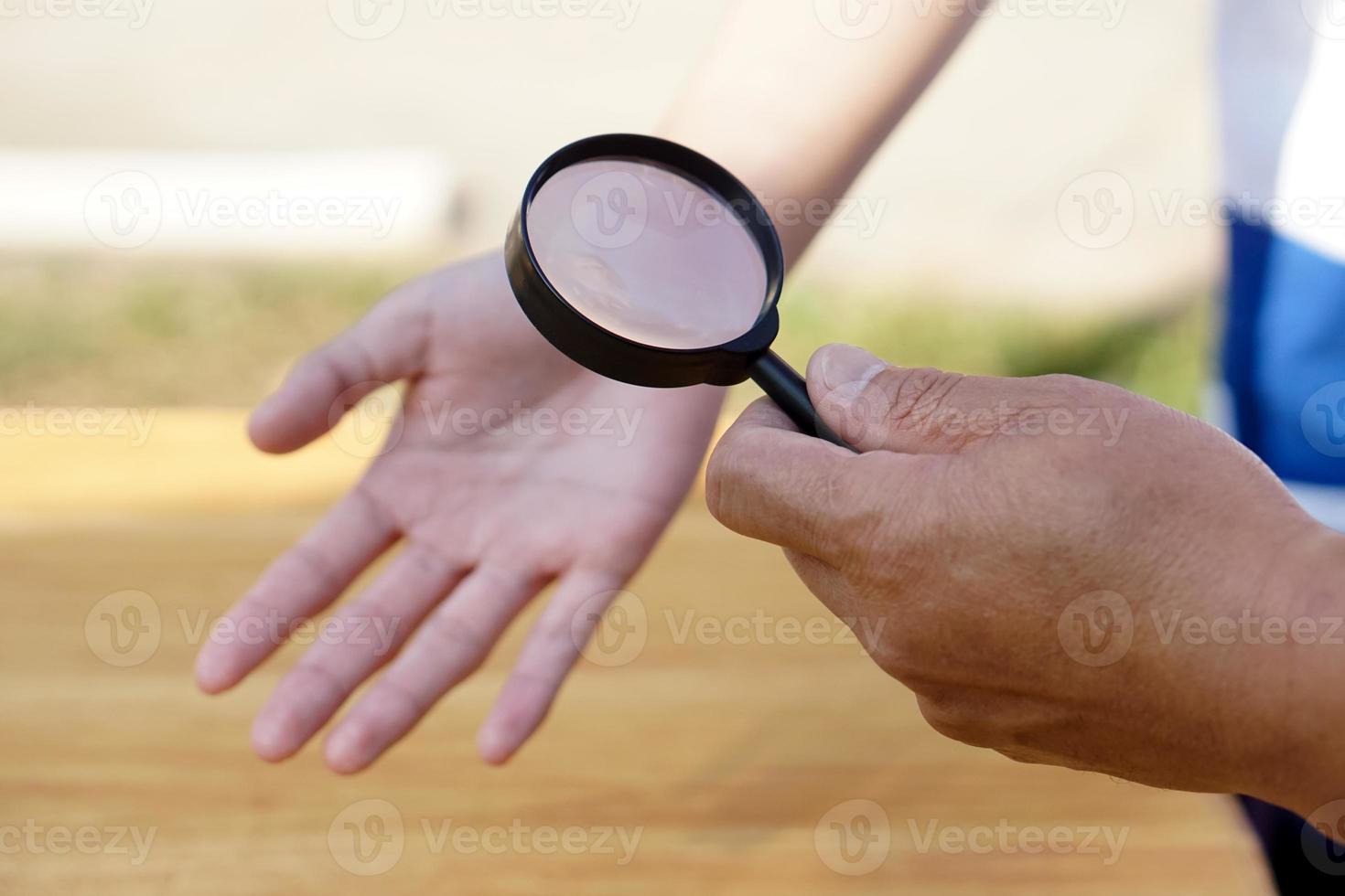 la mano de primer plano sostiene una lupa para inspeccionar las líneas de la palma. concepto, quiromancia, astrología. adivinación, misterio, magia, fortuna, destino. predicción para la vida futura, eventos. predicción palmista. foto