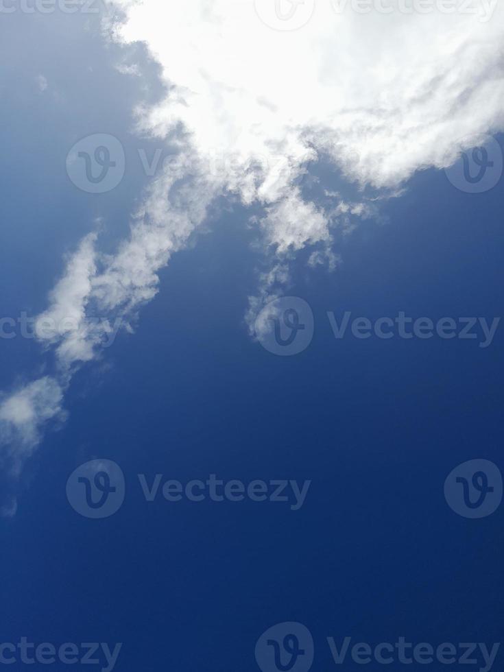 White clouds in the blue sky. Heaven and infinity. Beautiful bright blue background. Light cloudy, good weather. Curly clouds on a sunny day. photo
