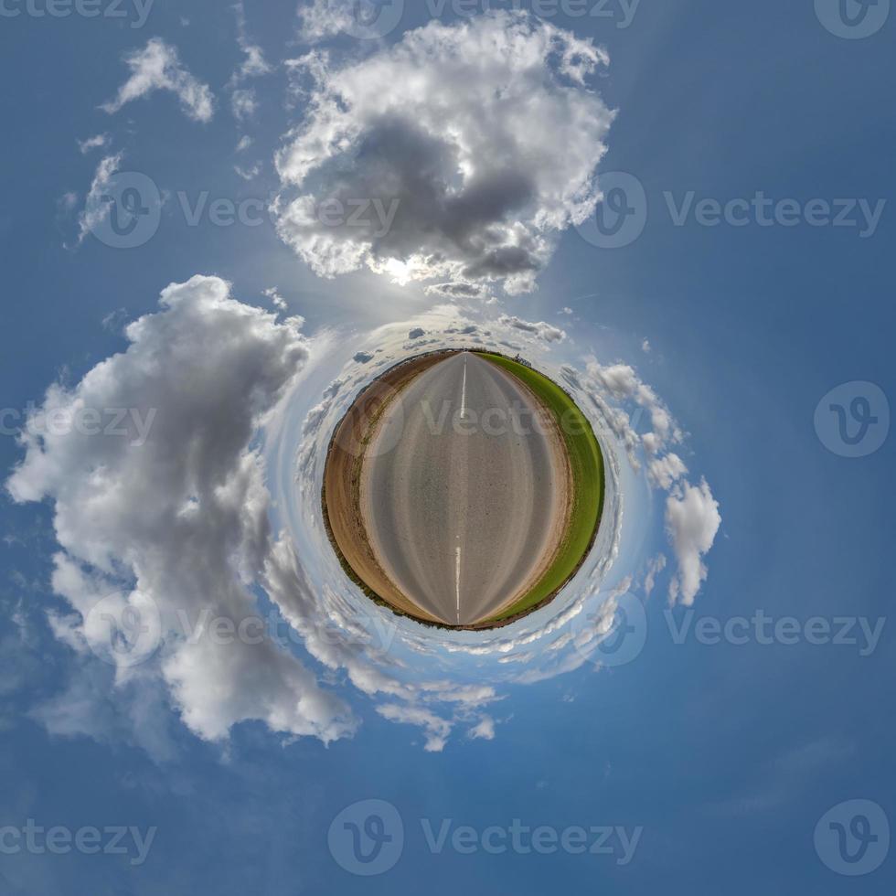 tiny planet in blue overcast sky with beautiful clouds with transformation of spherical panorama 360 degrees. Spherical abstract aerial view. Curvature of space. photo