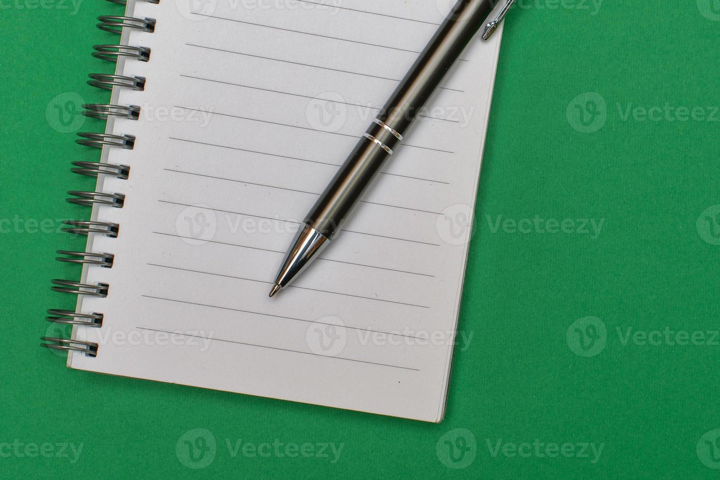 A notebook with a blank page and a pen resting on it photo