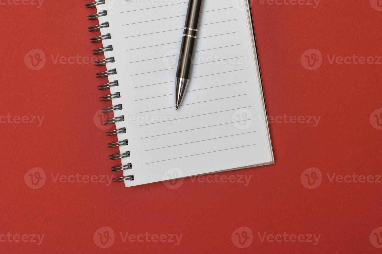 A notebook with a blank page and a pen resting on it photo