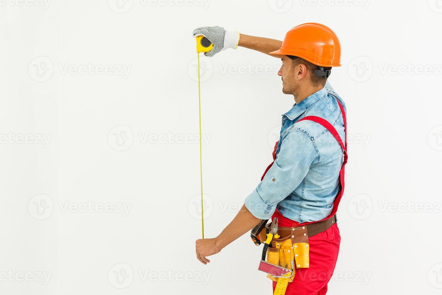 The builder in a helmet with a tape measure photo