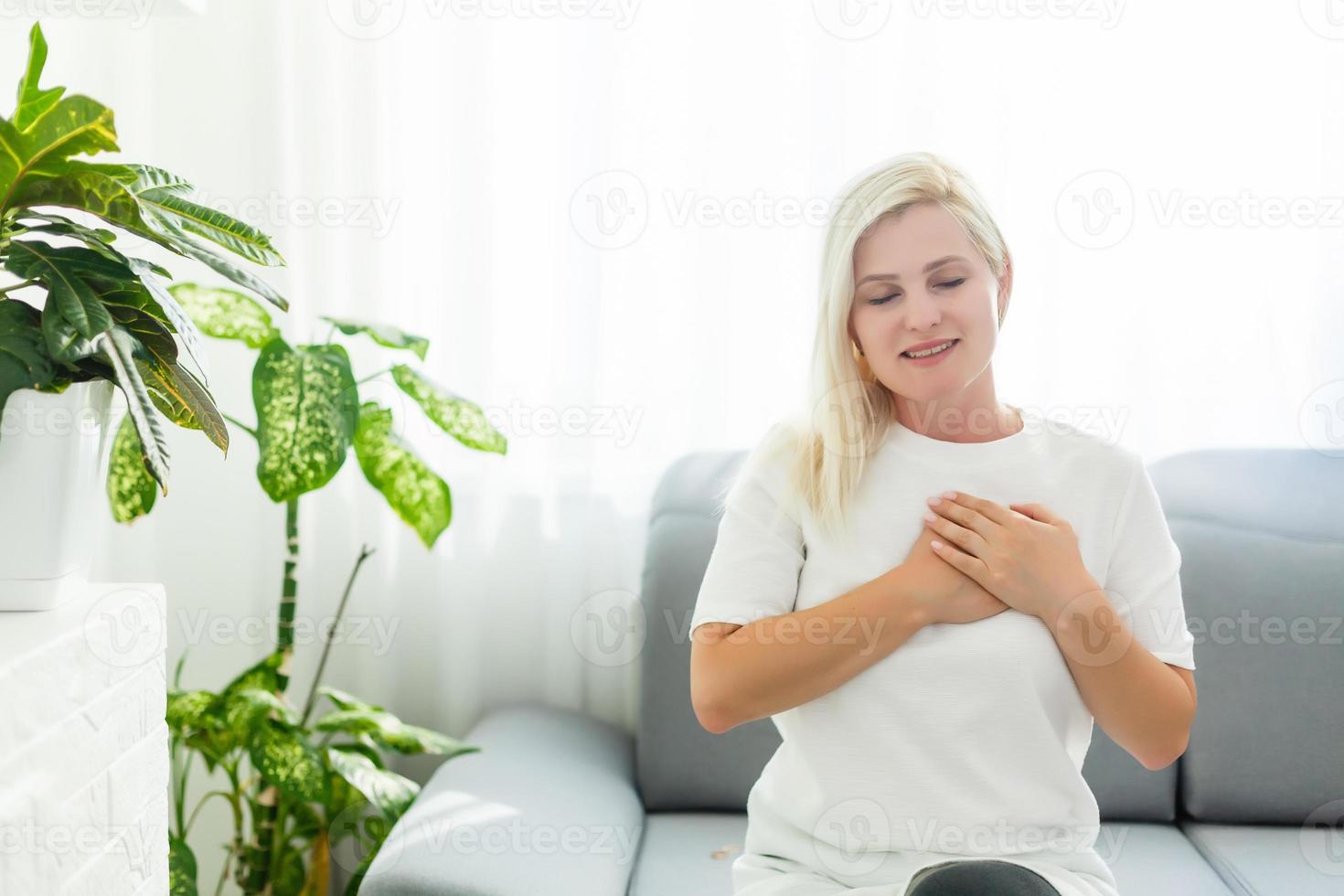 Religious faithful middle aged woman praying with hope faith holding hands clasped together in namaste at home in morning, old mature lady believer christian saying worship prayer with eyes closed photo