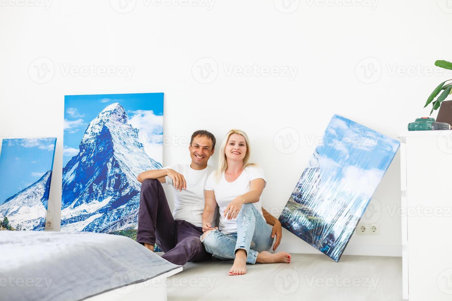 young couple hangs a large photo canvas at home