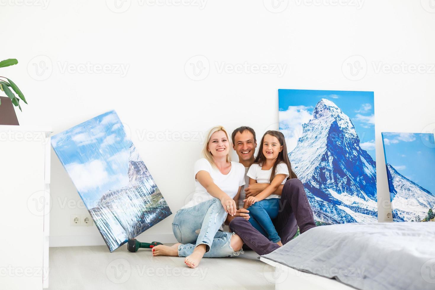 en una nueva familia plana cuelga un gran lienzo fotográfico en una pared blanca vacía en casa foto