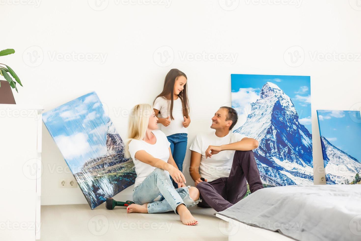 en una nueva familia plana cuelga un gran lienzo fotográfico en una pared blanca vacía en casa foto