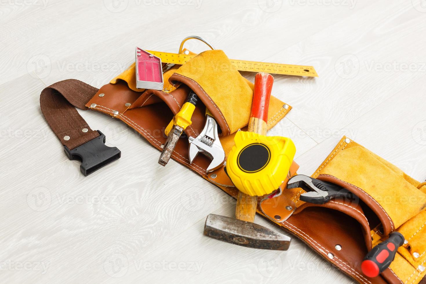 Leather tool belt with construction tooling on wooden board maintenance concept. photo