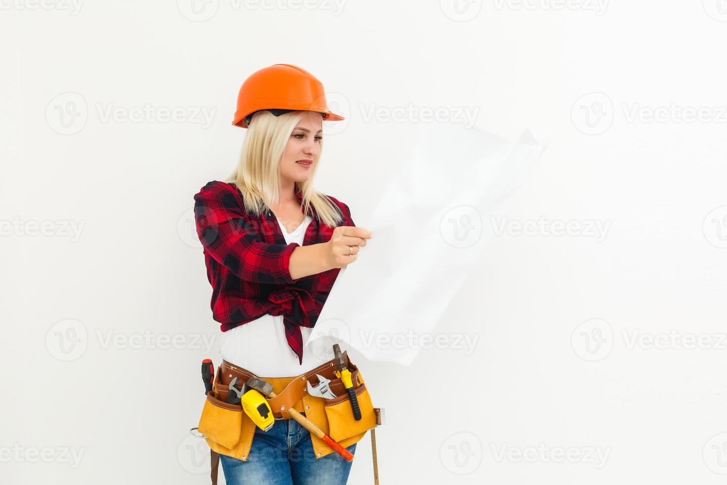 Young female construction specialist reviewing blueprints at construction site photo