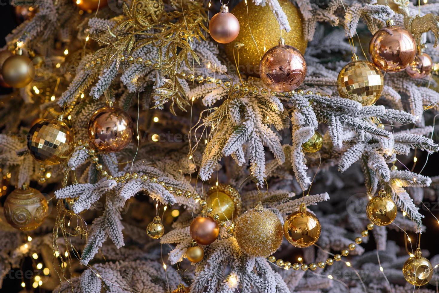 hermoso árbol de navidad con guirnaldas, pelotas y juguetes foto