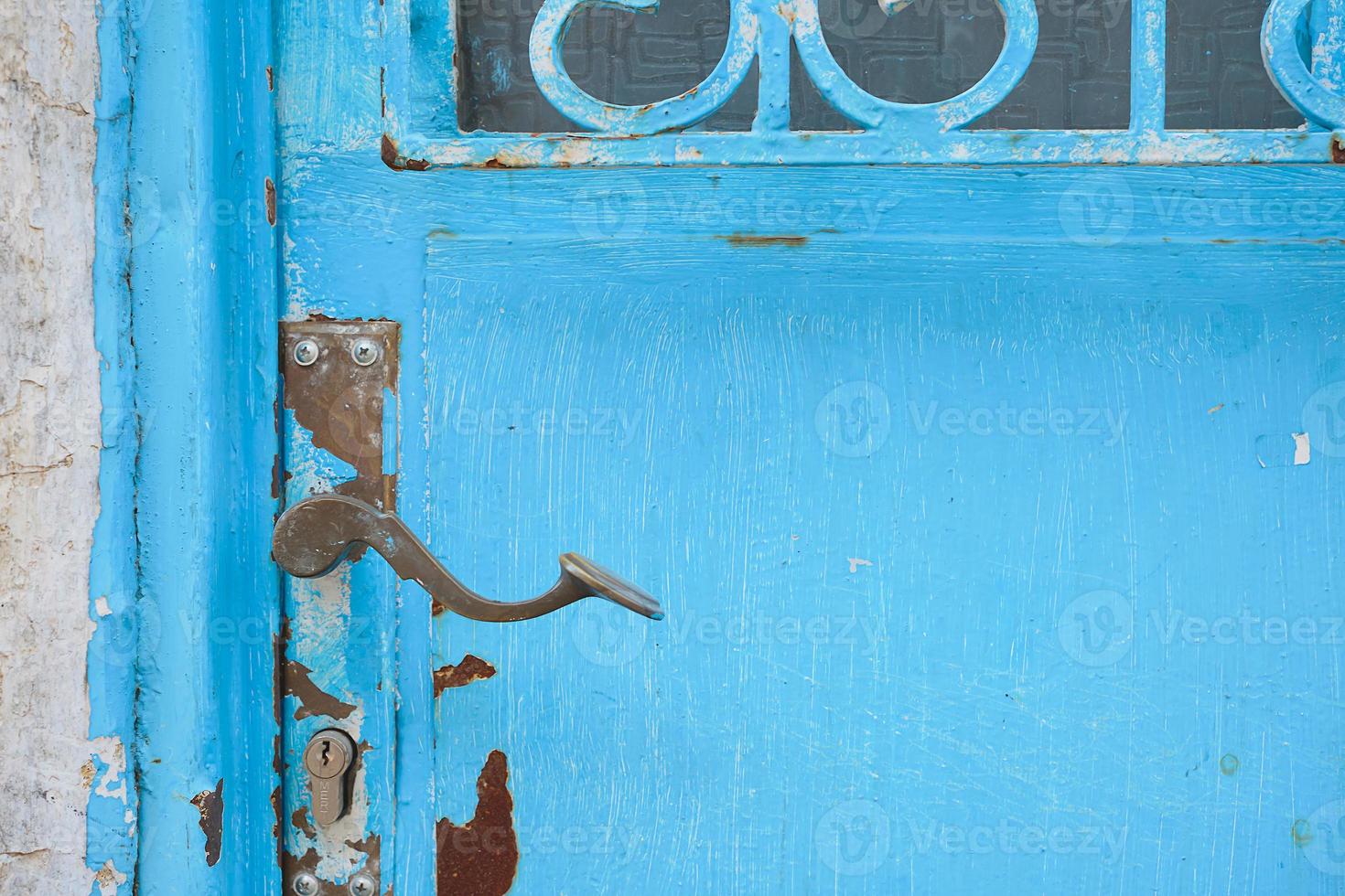 Details of an old metal door painted with blue paint, selective focus on the handle of the door, ideas for a background or interior, renovation of old houses photo