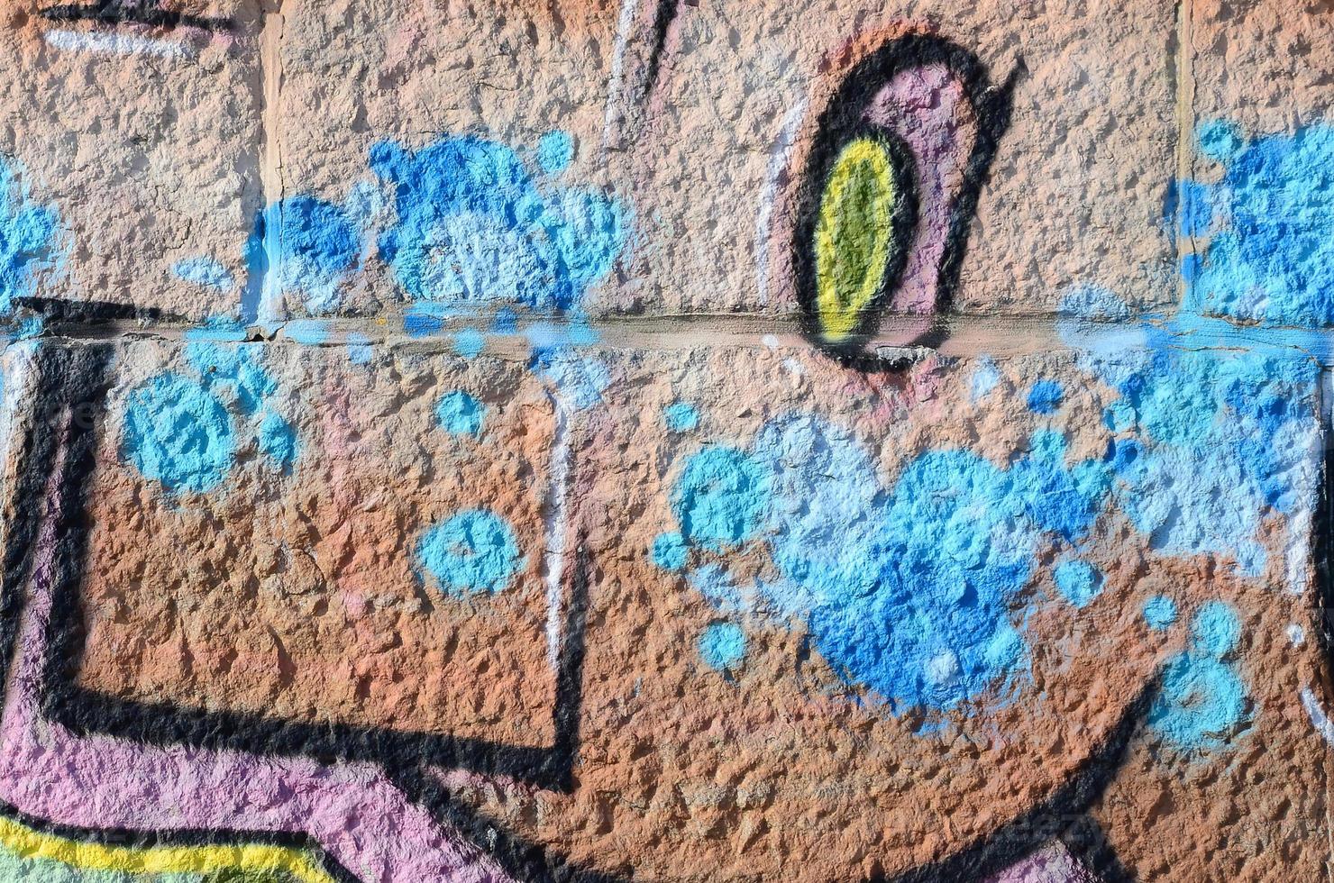 fragmento de dibujos de graffiti. la antigua muralla decorada con manchas de pintura al estilo de la cultura del arte callejero. textura de fondo coloreada en tonos cálidos foto