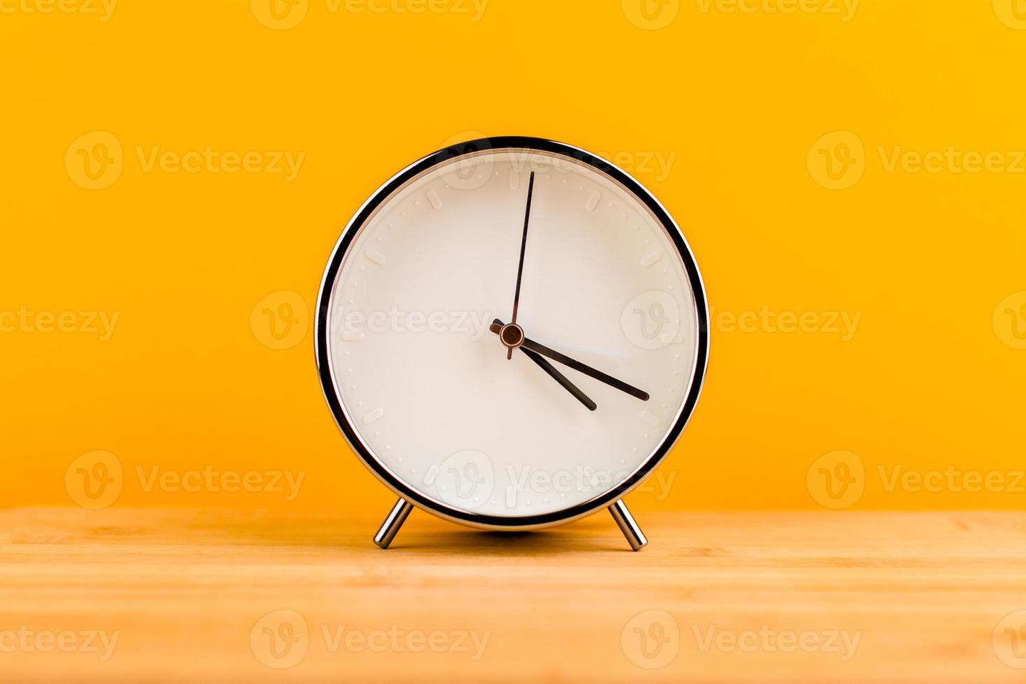 Alarm clock on yellow background, time concept photo