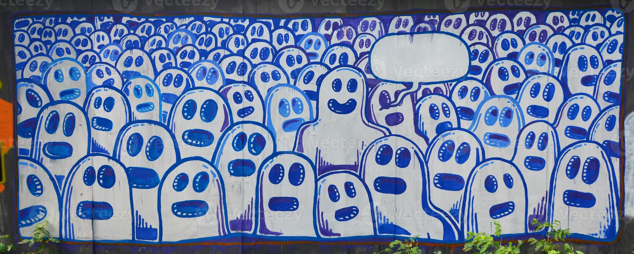 The old wall, painted in color graffiti drawing with aerosol paints. The image of a set of identical cartoon faces as concept of senseless crowd with one outstanding character and a cloud for speech photo