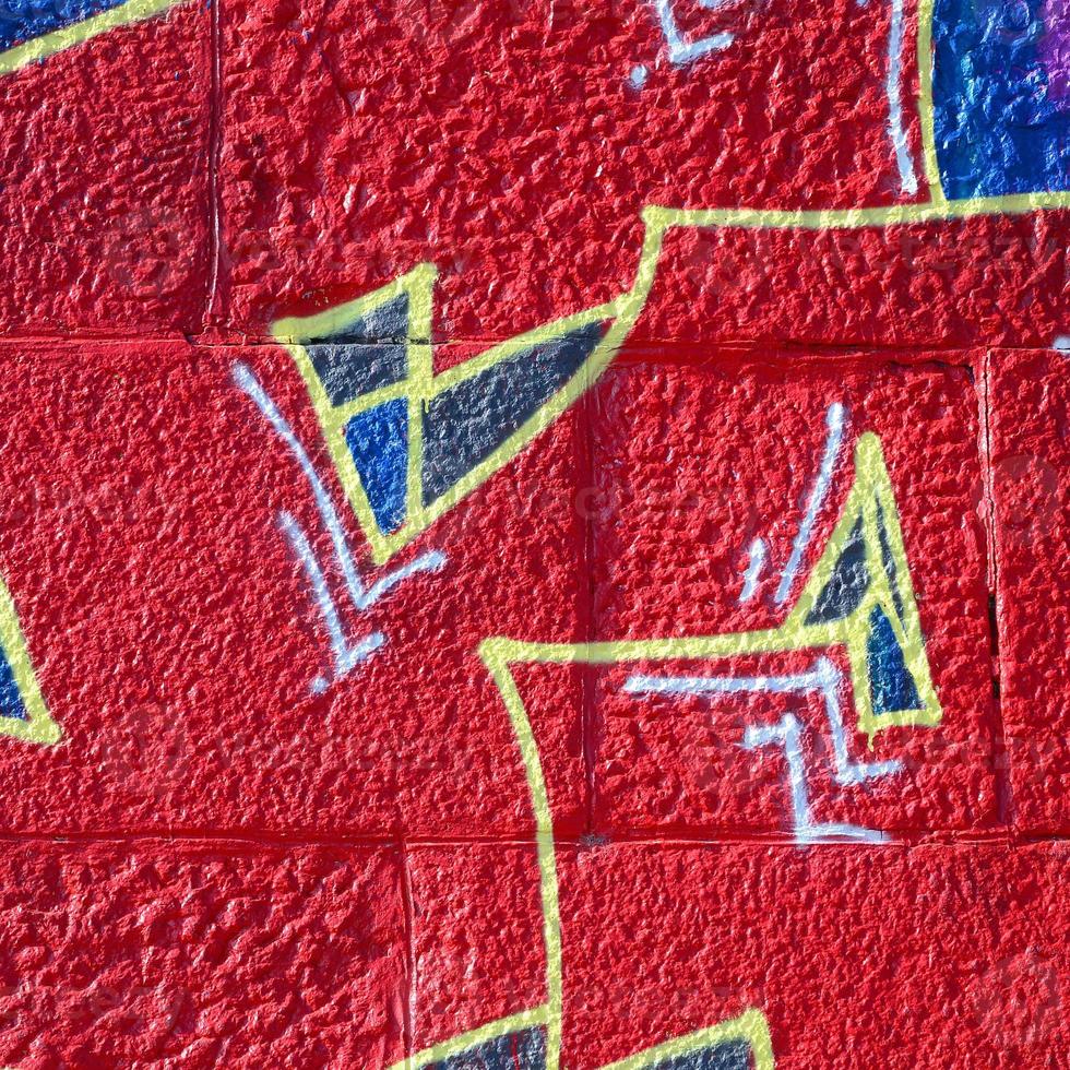 fragmento de dibujos de graffiti. la antigua muralla decorada con manchas de pintura al estilo de la cultura del arte callejero. textura de fondo coloreada en tonos cálidos foto