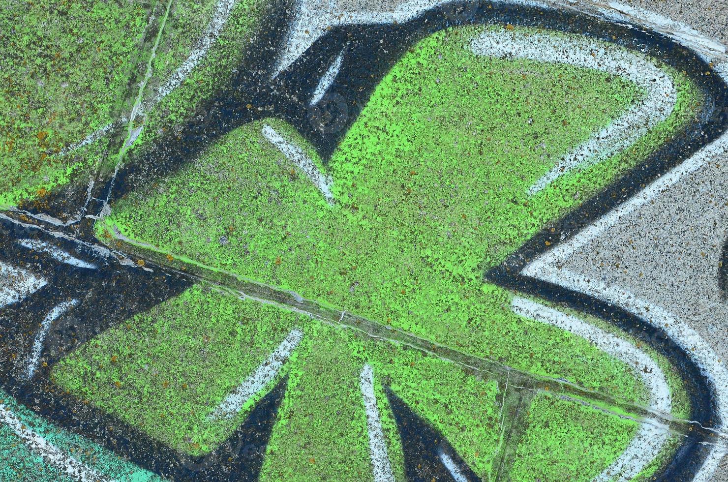 Fragment of graffiti drawings. The old wall decorated with paint stains in the style of street art culture. Colored background texture in green tones photo