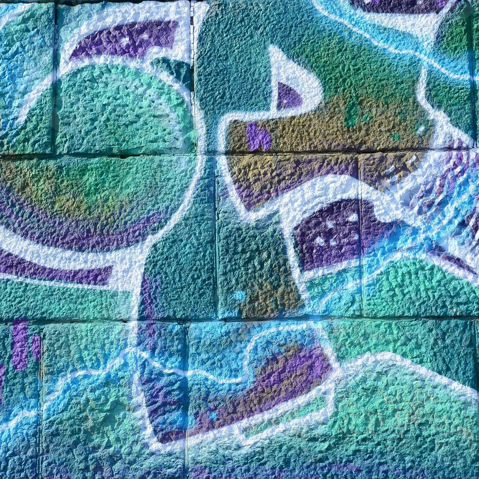 fragmento de dibujos de graffiti. la antigua muralla decorada con manchas de pintura al estilo de la cultura del arte callejero. textura de fondo coloreada en tonos fríos foto