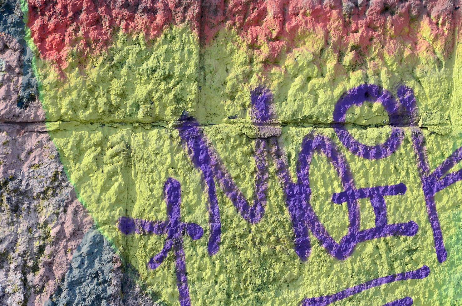 Fragment of graffiti drawings. The old wall decorated with paint stains in the style of street art culture. Colored background texture in warm tones photo