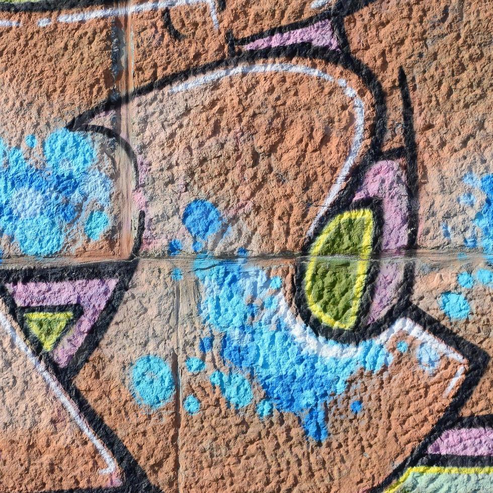 fragmento de dibujos de graffiti. la antigua muralla decorada con manchas de pintura al estilo de la cultura del arte callejero. textura de fondo coloreada en tonos cálidos foto