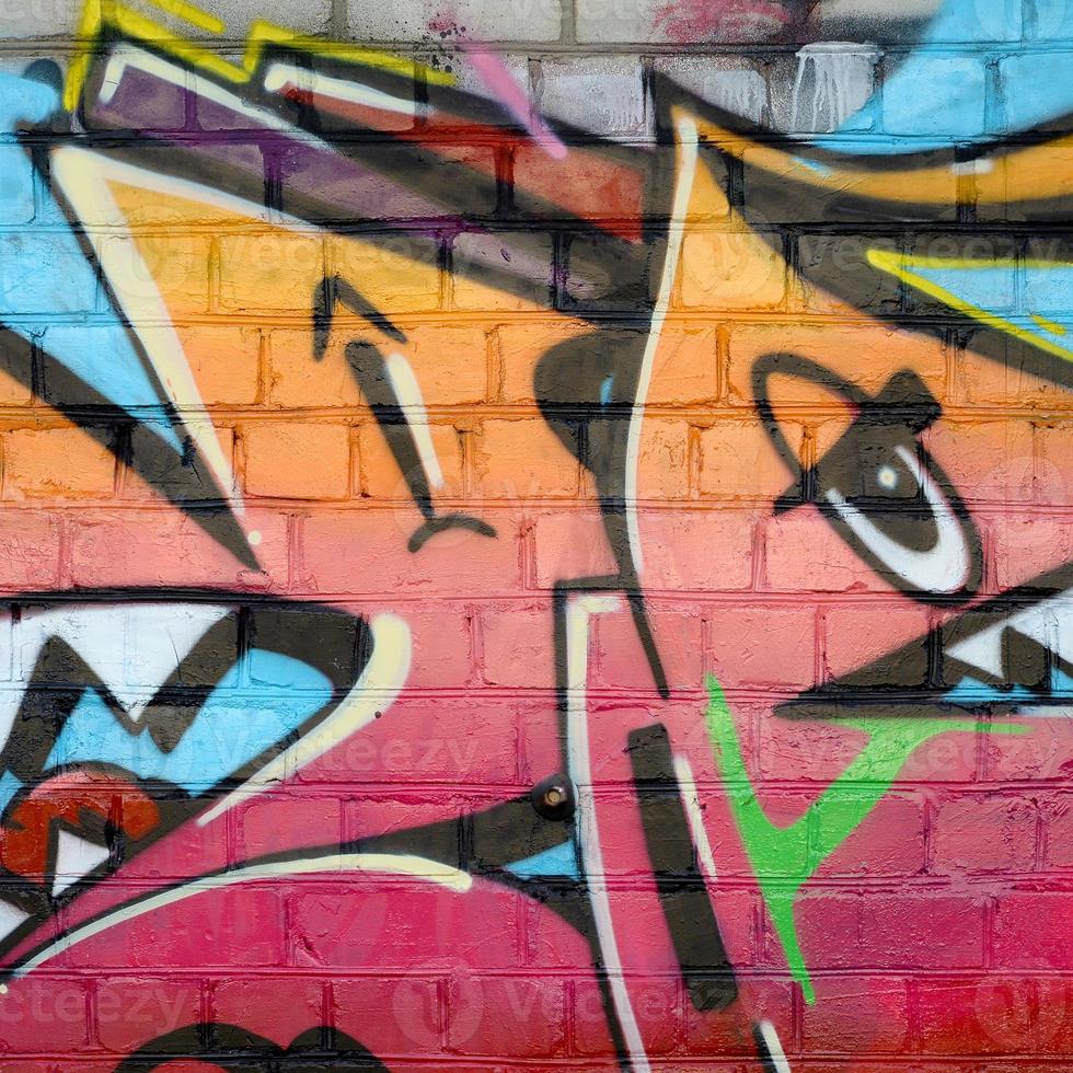 Abstract colorful fragment of graffiti paintings on old brick wall. Street-art composition with parts of wild letters and multicolored stains. Subcultural background texture photo