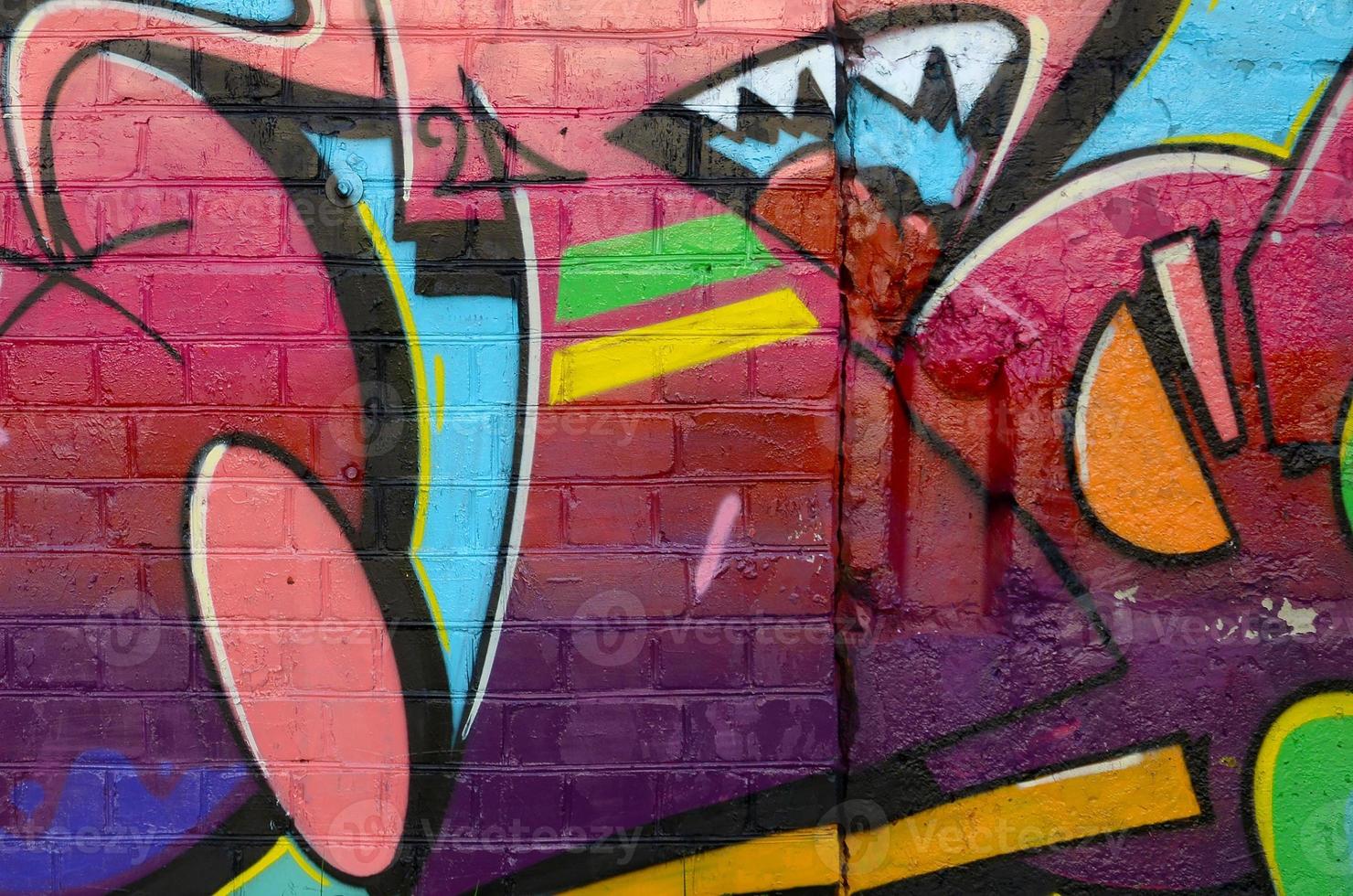 Abstract colorful fragment of graffiti paintings on old brick wall. Street-art composition with parts of wild letters and multicolored stains. Subcultural background texture photo